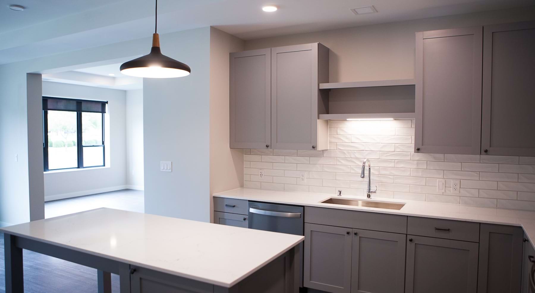 Kitchen with grey cabinets and white tiled backsplach