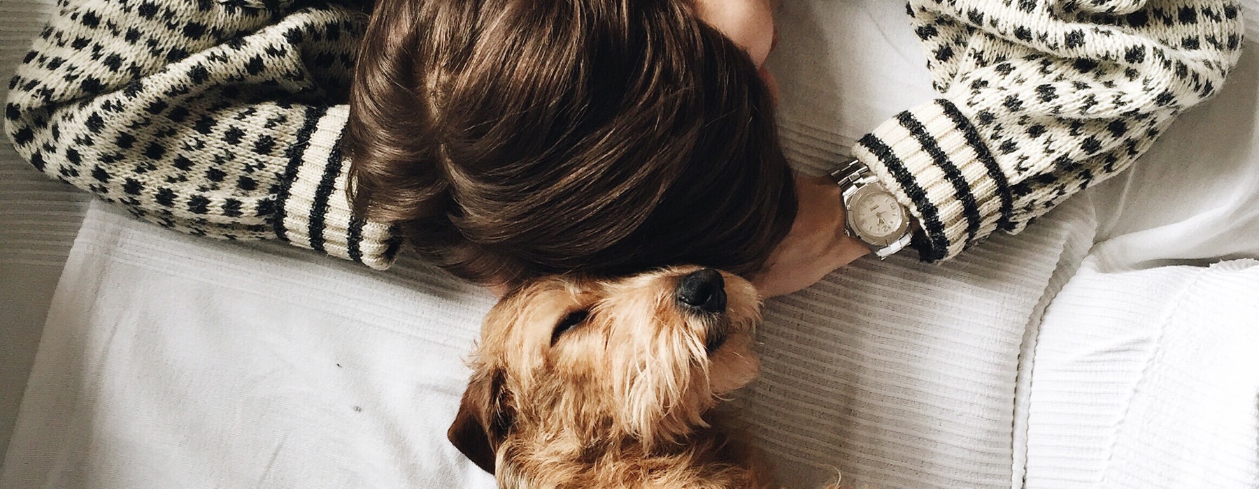 girl and dog laying head to head on bed